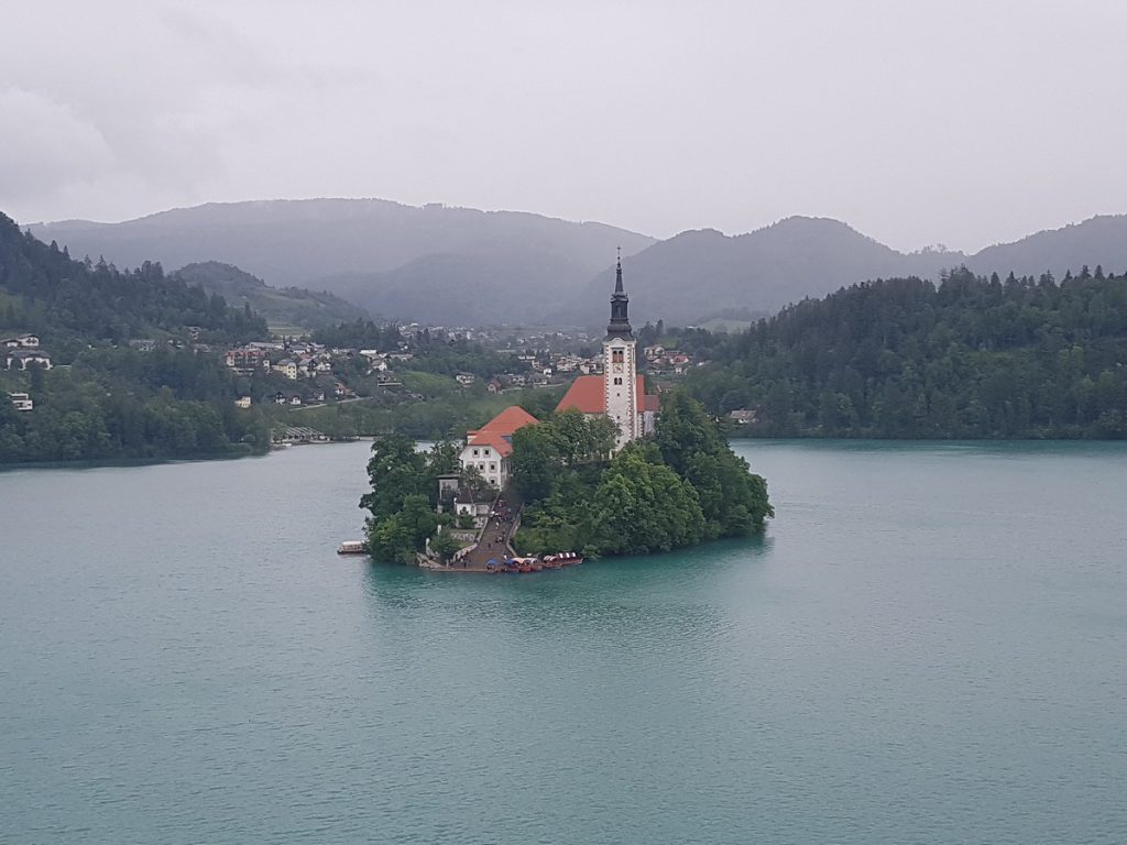 Kirche auf Insel mit Alpen im Hintergrund
