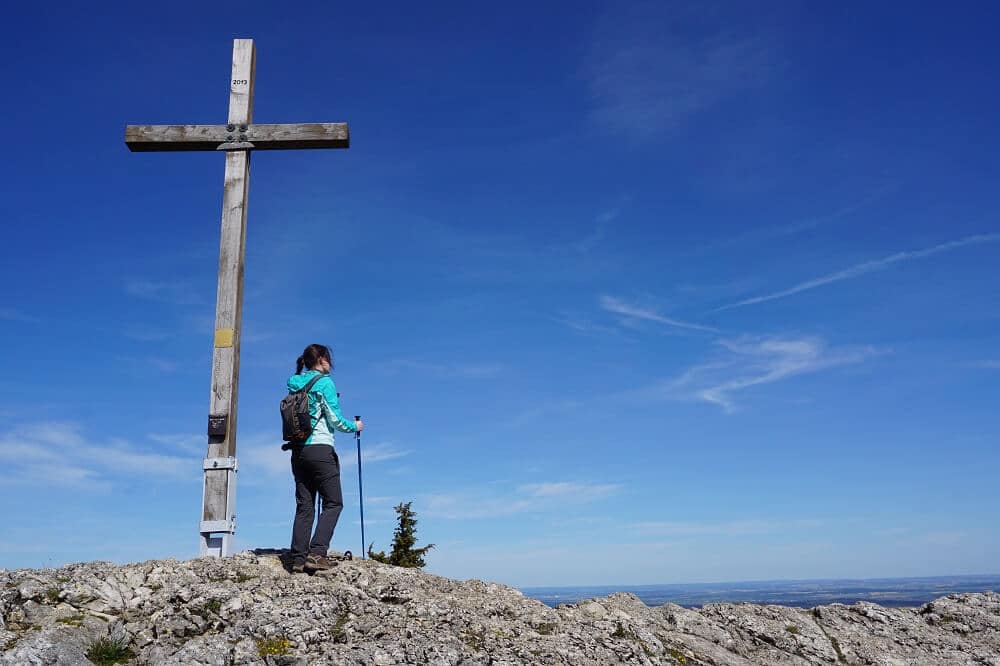 Junge Frau genießt die Aussicht vom Gipfelkreuz