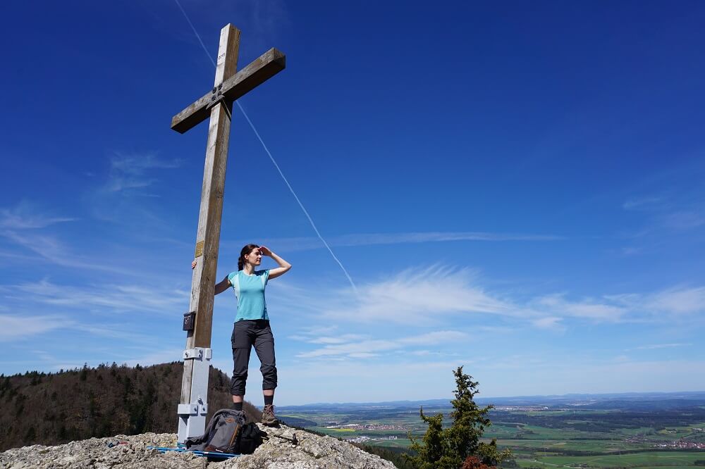 Frau mit gutem Wanderoutfit und Kleidung am Gipfelkreuz