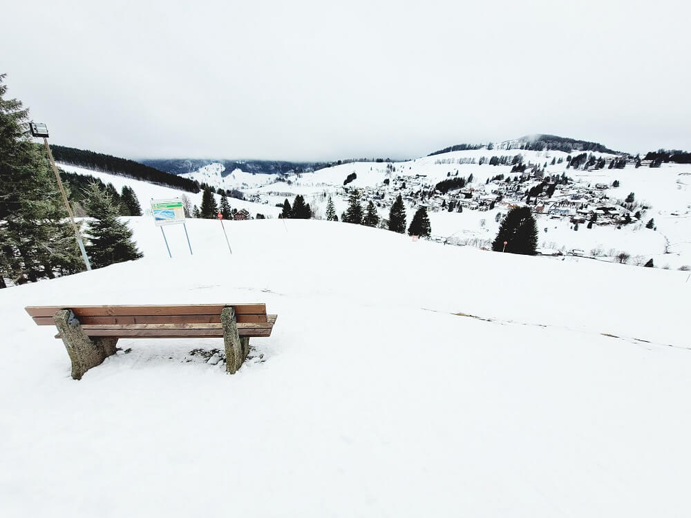 Sitzbank im Schnee mit schöner Aussicht