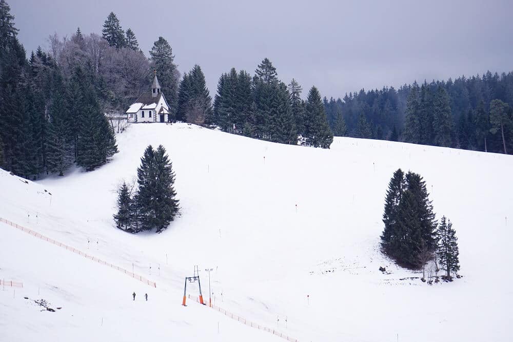 Kapelle und Skihang in verschneiter Winterlandschaft