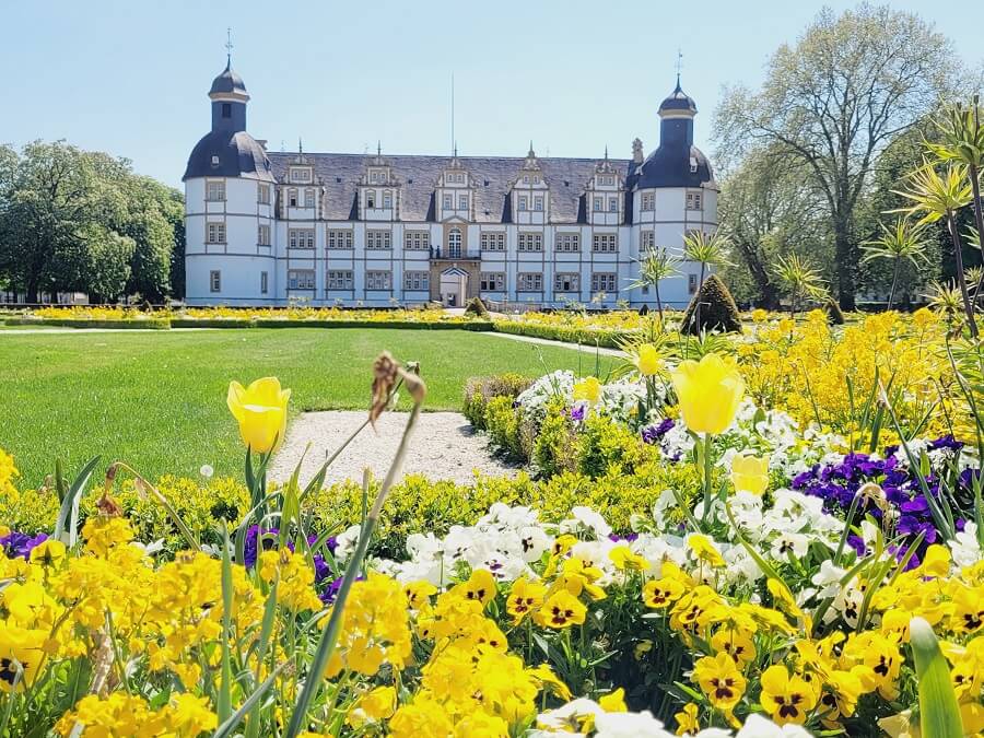 Schloss Neuhaus mit vielen bunten Blumen im Vordergrund