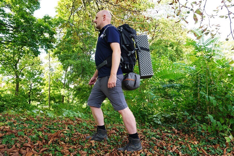 Mann trägt komplette Camping Grundausstattung auf dem Rücken
