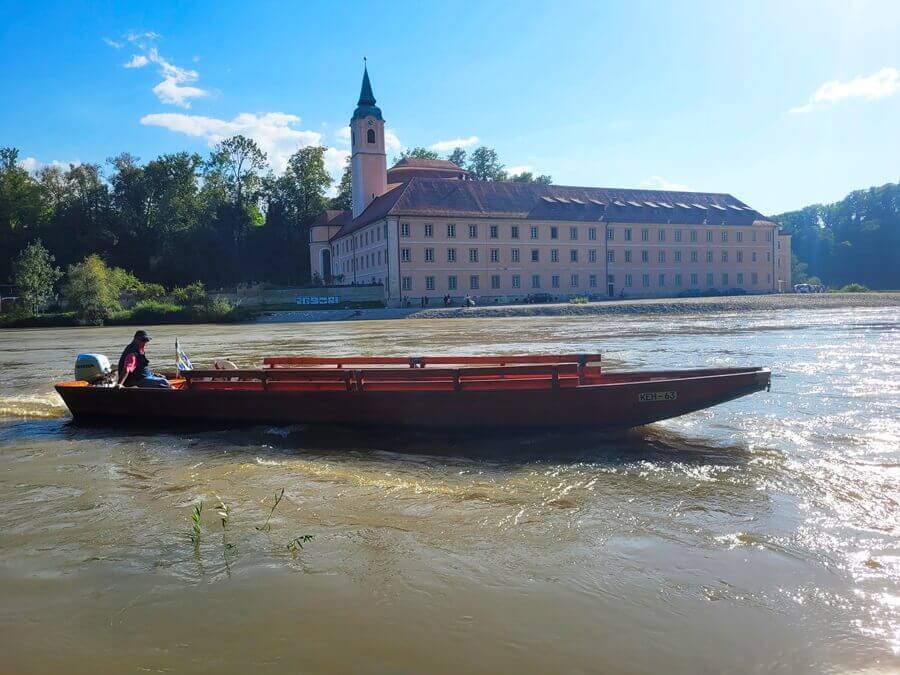 Mit der Zille wird zum anderen Ufer übergesetzt. Kleines Boot auf einem Fluss vor einem Kloster