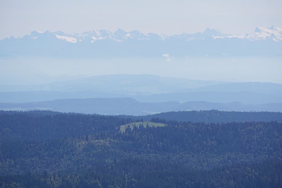Im Hintergrund die Alpen, im Vordergrund der Blößling mit Gipfelkreuz und Schutzhütte. Auch zum Blößling führt einer der "Hidden Trails"-Wanderwege im Schwarzwald!